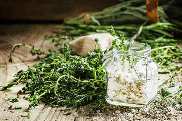 Traditional spicy salt with thyme in a glass jar, vintage wooden