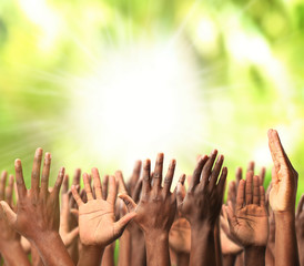 Crowd raising hands on green blurred nature background