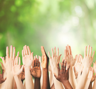 Crowd raising hands on green blurred nature background