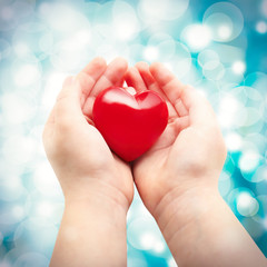 Heart in child hands on bokeh background