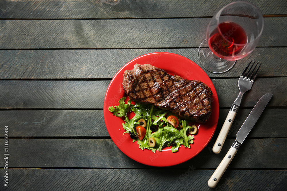 Sticker Grilled steak with vegetable salad and glass of wine, closeup