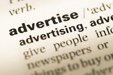 Obraz premium Close up of old English dictionary page with word advertise