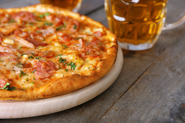 Delicious pizza  and glasses of beer are on wooden table, close up