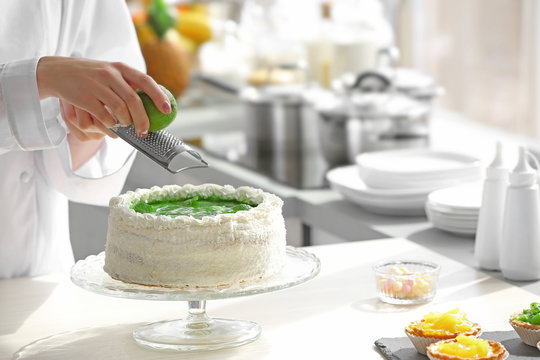 Female hands decorating cake  with lime zest
