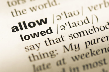 Obraz premium Close up of old English dictionary page with word allow