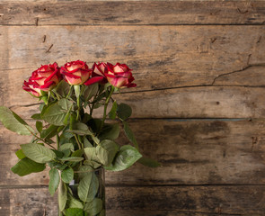 Fototapeta na wymiar Bunch of red roses in vase on wooden background