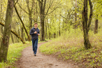 Obraz premium Young sporty man jogging in the morning forest