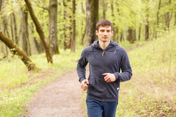 Young sporty man jogging in the morning forest