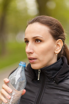 Young woman drinking water after workout jogging
