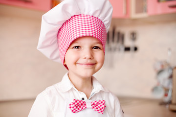 portrait of little boy in the hat of the chef and an apron. Little chef cooks in the...