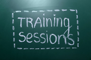 Training sessions inscription written with white chalk on blackboard