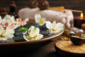 Fototapeta na wymiar Spa wooden bowl with water, flowers and stones closeup