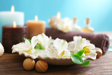 Fototapeta na wymiar Spa set: soft towel, flowers, massage oil, candles, sea salt, close up