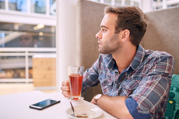 Fototapeta na wymiar Handsome man looking sideways while holding his tea in cafe