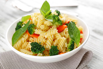 Boiled fusilli pasta with carrot, broccoli and basil on white plate
