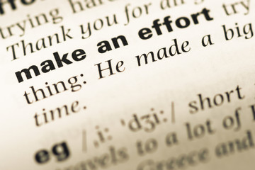 Obraz premium Close up of old English dictionary page with word make an effort