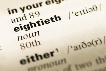 Close up of old English dictionary page with word eightieth