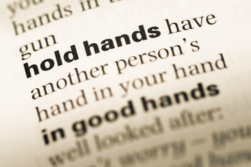 Close up of old English dictionary page with word hold hands