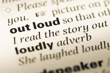 Obraz premium Close up of old English dictionary page with word out loud