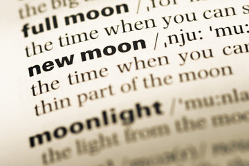 Close up of old English dictionary page with word new moon