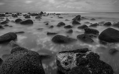Longue exposition en noir et blanc des vagues s& 39 écoulant sur les roches volcaniques à Hawaï.