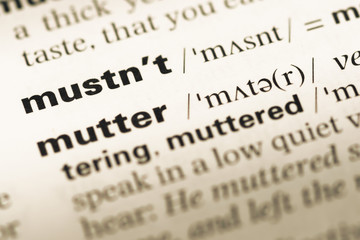 Fototapeta premium Close up of old English dictionary page with word mustn't