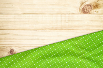 Green tablecloth on wooden table with copy space.