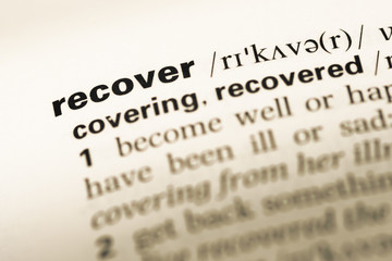Close up of old English dictionary page with word recover