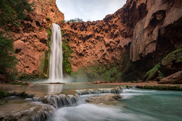 The impressive flow of Mooney Falls at the bottom of the Havasupai Canyon in the desert of Arizona.