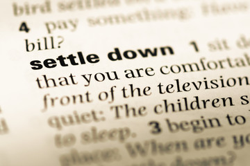 Fototapeta premium Close up of old English dictionary page with word settle down