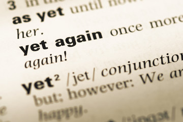 Close up of old English dictionary page with word yet again