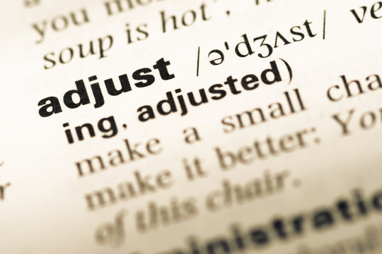 Close up of old English dictionary page with word adjust