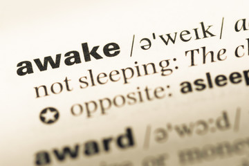 Close up of old English dictionary page with word awake