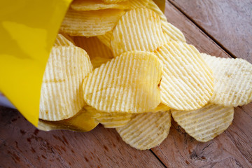Opened pack with potato chips over wooden table