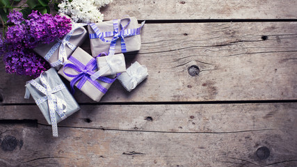 Wrapped  gift boxes with presents  and lilak flowers on aged woo