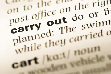 Fototapeta premium Close up of old English dictionary page with word carry out
