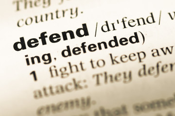 Obraz premium Close up of old English dictionary page with word defend