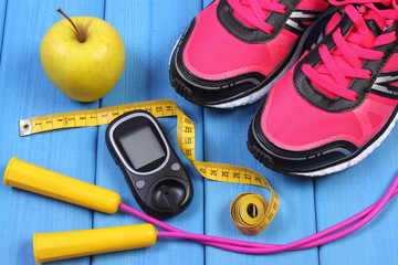 Fototapeta na wymiar Glucometer, sport shoes, fresh apple and accessories for fitness on blue boards