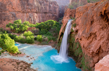 A view of Havasu Falls from the hillside above the falls. The turquoise colored water flowing in to...