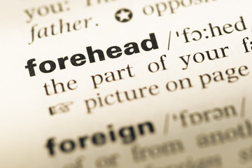 Obraz premium Close up of old English dictionary page with word forehead