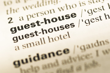 Fototapeta premium Close up of old English dictionary page with word guest house