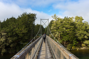 Fototapeta na wymiar woman hiking on swing bridge at Kepler track