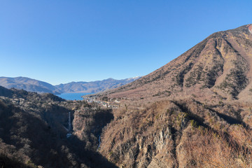 Mountain, blue lake (Lake Chuzenji), great falls (Kegon waterfall) under blue sky. Photo taken from Akechi-daira observatory, Nikko National Park, Tochigi Prefecture, Japan.