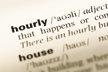 Close up of old English dictionary page with word hourly