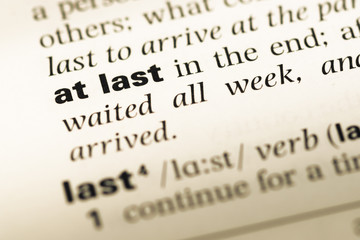 Obraz premium Close up of old English dictionary page with word at last