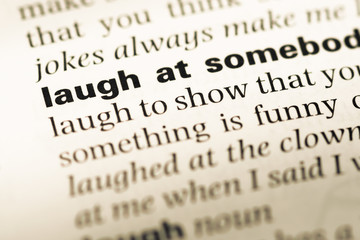 Close up of old English dictionary page with word laugh at