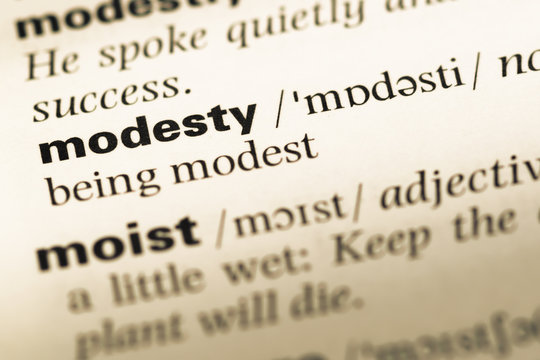 Close up of old English dictionary page with word modesty