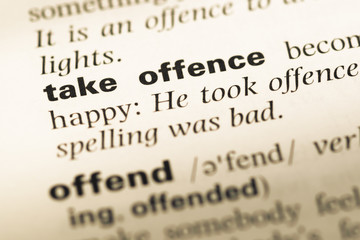 Close up of old English dictionary page with word take offence