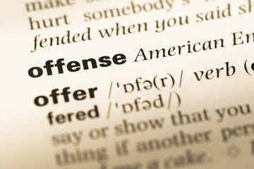 Fototapeta premium Close up of old English dictionary page with word offense