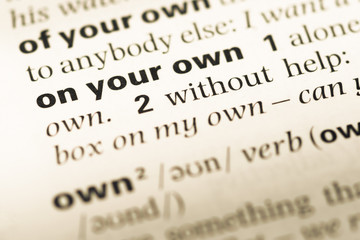 Close up of old English dictionary page with word on your own